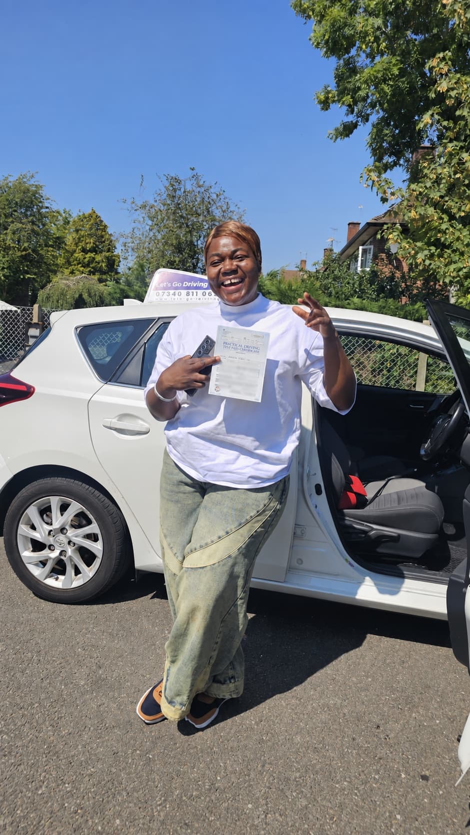 A pupil celebrating after passing their driving test beside the Let's Go Driving car