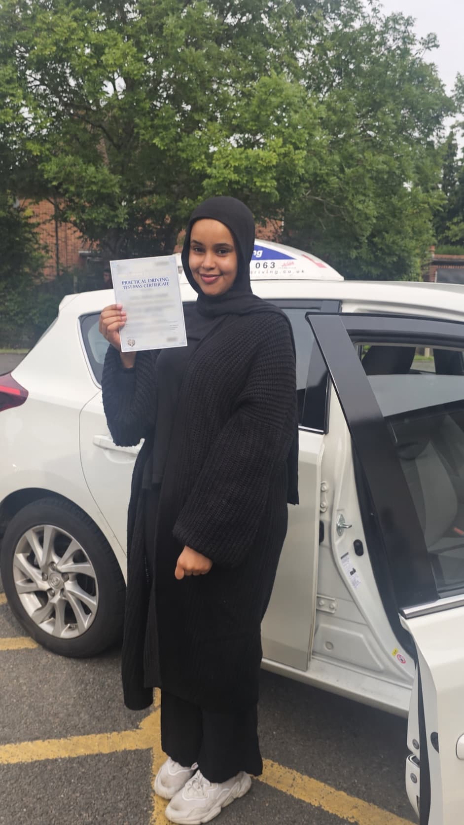 A pupil celebrating after passing their driving test beside the Let's Go Driving car